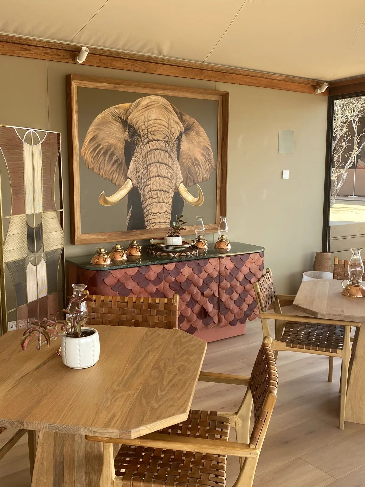 Dining interior at Noka Camp with woven leather chairs and elephant artwork