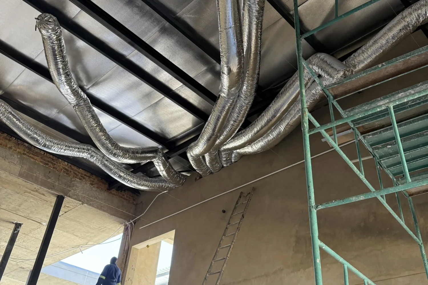 Insulated HVAC ducting routed through the double-volume ceiling void at first fix
