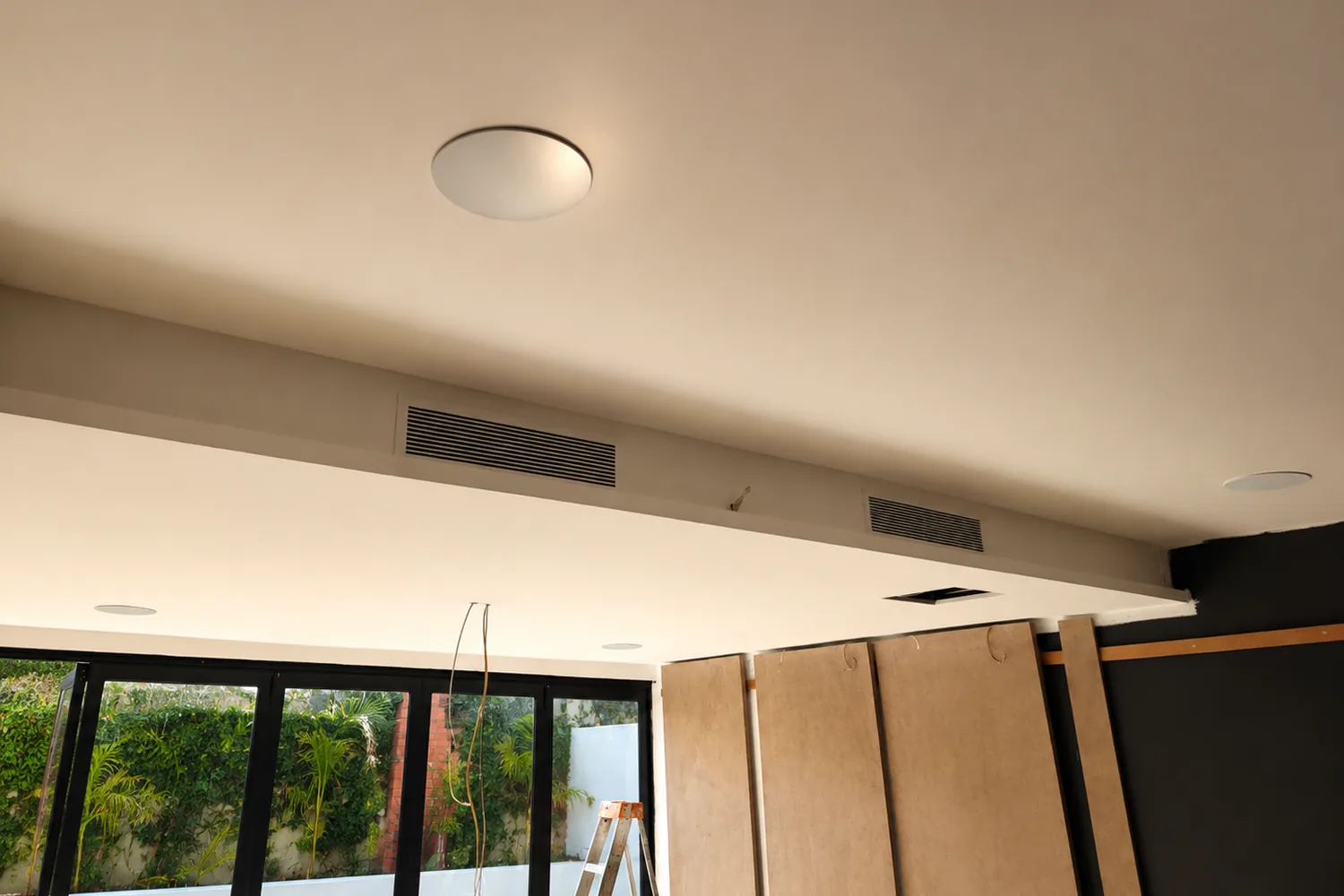Cinema ceiling with overhead speaker and a linear HVAC grille, services concealed within the bulkhead
